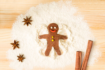 Top-down view of a gingerbread man making a snow angel on flour.