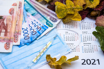 Calendar and face mask. Thermometer and autumn leaves on a white background.