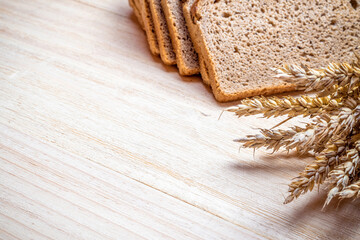 Fototapeta na wymiar Rye bread isolated. Bakery with crusty loaves and crumbs. Fresh loaf of rustic traditional bread with wheat grain ear or spike plant on natural wooden background. Bio ingredients, healthy with seeds.