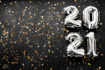 Inflatable numbers New Year 2021 on the right. Black background with shiny golden and silver stars. Copy space