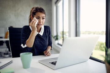 Crying businesswoman making video call over laptop while working in the office.