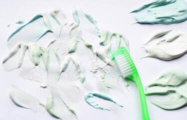 Green toothbrush and toothpastes in three colors: green sweet mint, blue strong mint and white-whitening. White background, copy space. The concept of oral hygiene