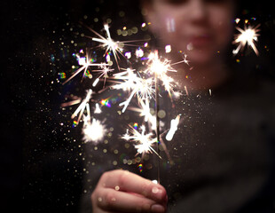 Christmas party. Сhild holds lighted fireworks in glitter background with bright golden Christmas...