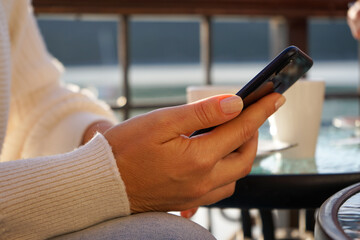 A woman in a cafe uses a smartphone