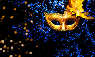 Masquerade mask on dark background with blue sparkles. The concept of traditional holidays....