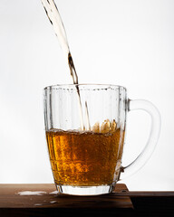 Beer pouring into glass on white background