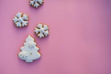Christmas gingerbreads in the form of trees and snowflakes on a pink background.
Composition with empty space for text; top view, flat lay.