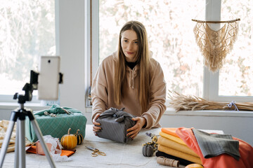 Woman wraps Furoshiki gift in zero waste style and record vlog, master class on cell phone....