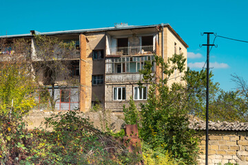 Building at Sushi (Shusha) in Nagorno Karabakh in very poor condition with vegetation growing wild on the street