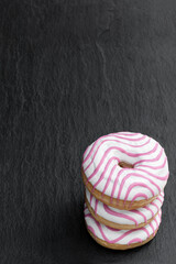 Colourful glazed striped doughnut on black stone background
