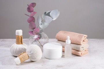 Fototapeta na wymiar Set of massage bags with herbs, cream and towels in light colors.