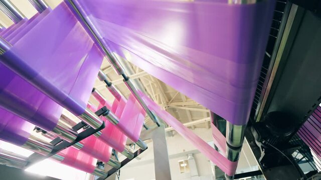 Bottom view of a colourful plastic bag making machine at a polyethylene production factory. Polyethylene bag production.