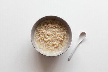 Homemade oatmeal porridge with milk in a bowl on a white background. Health nutrition food concept