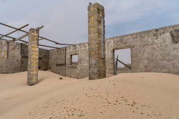 Ruined stone building with standing pillars and partial walls in the desert of Oman