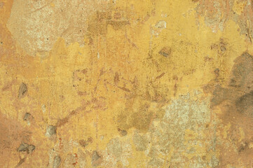 A large fragment of the yellow clay wall of the old house with cracks and roughness, exfoliating part of the plaster. Vintage background. Rough flushed texture. Space to copy text.