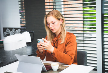 Private Kontakte während der Arbeitszeit - junge Angestellte checkt im Büro Nachrichten auf dem...