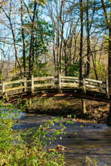 A Wooden Bridge Going Over a Small Stream on a Clear Autumn Day