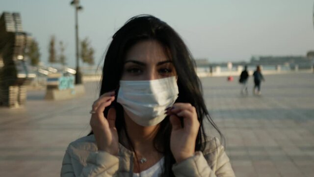 brunette Girl in mask in outdoor look to the mobile phone and wear the mask