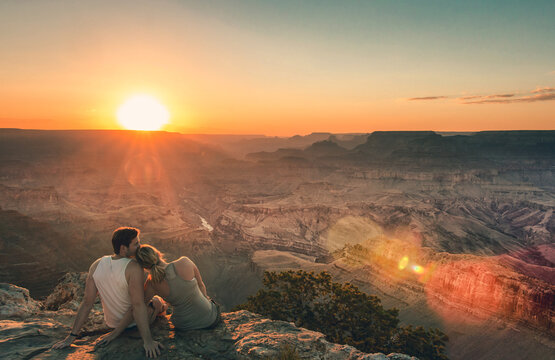 Paar sitzt am Rand des Grand Canyons bei Sonnenuntergang.