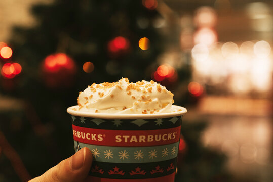 A Cup of coffee with cream in Starbucks on the background of the Christmas tree