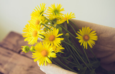 yellow flowers in a basket on a wooden background