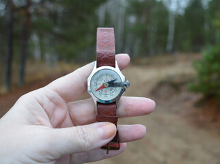 a woman's hand on the hunt holds a compass to determine the location