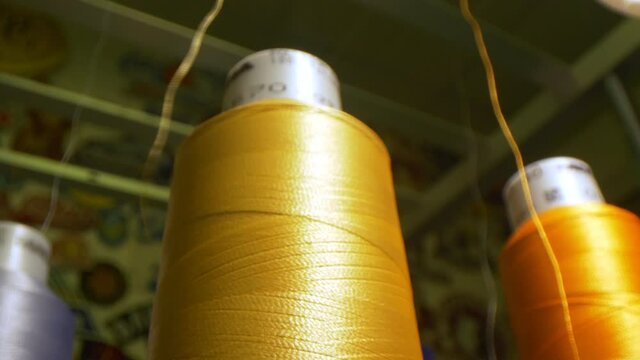 Golden thread uncoiling from spool by machine tool in shop