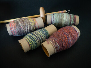 thread of spun wool wrapped around cardboard bobbins and wooden spindle