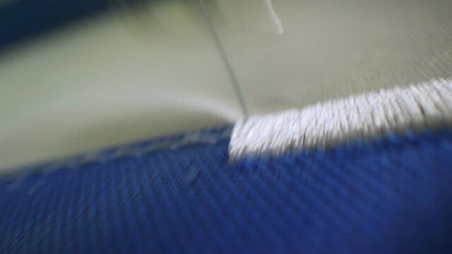 Machine embroiders pattern on uniform with white threads