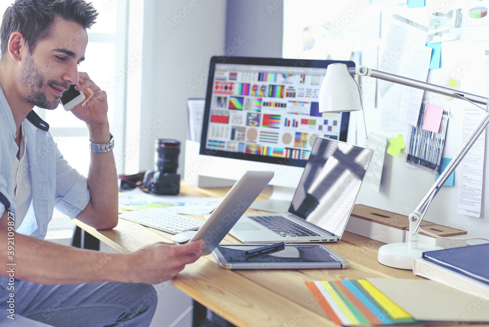 Poster portrait of young designer sitting at graphic studio in front of laptop and computer while working o