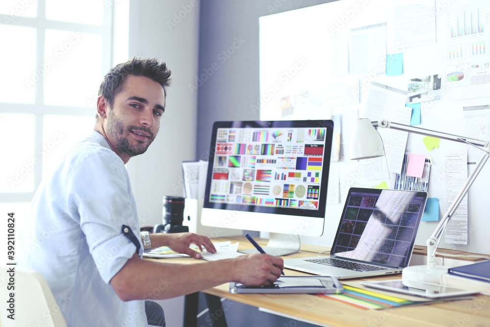 Aufkleber portrait of young designer sitting at graphic studio in front of laptop and computer while working o