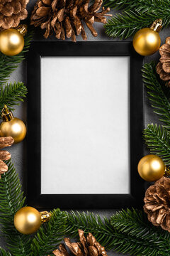 Christmas composition with empty picture frame. Golden ornament, pine cones and fir needles decorations. Mock up greetings card template