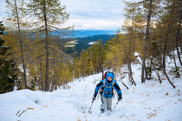Female mountaineer in full winter gear surrounded with snowy forest.