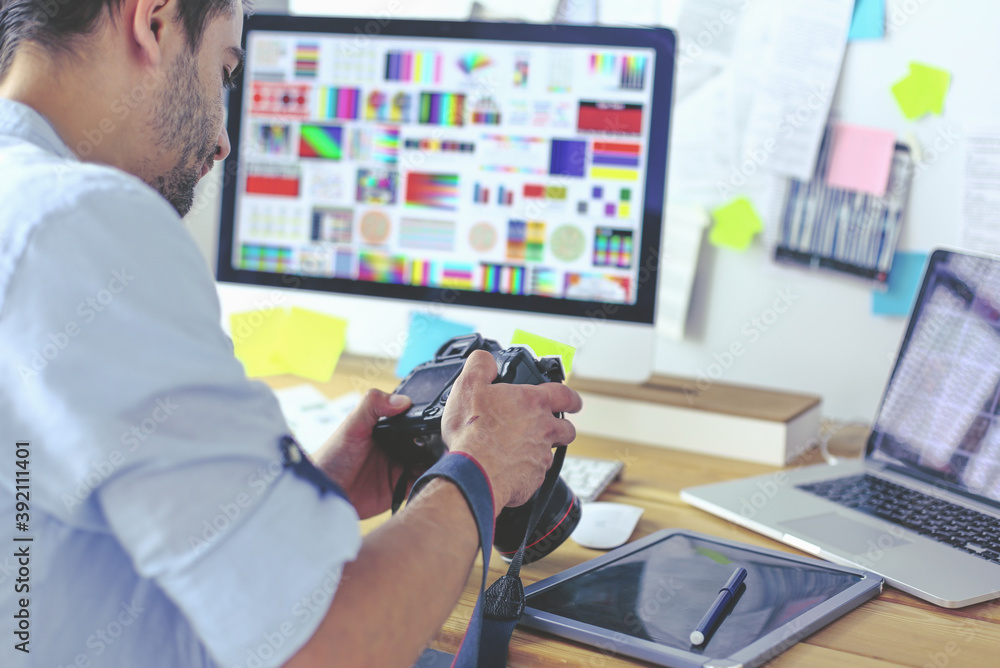 Poster portrait of young designer sitting at graphic studio in front of laptop and computer while working o