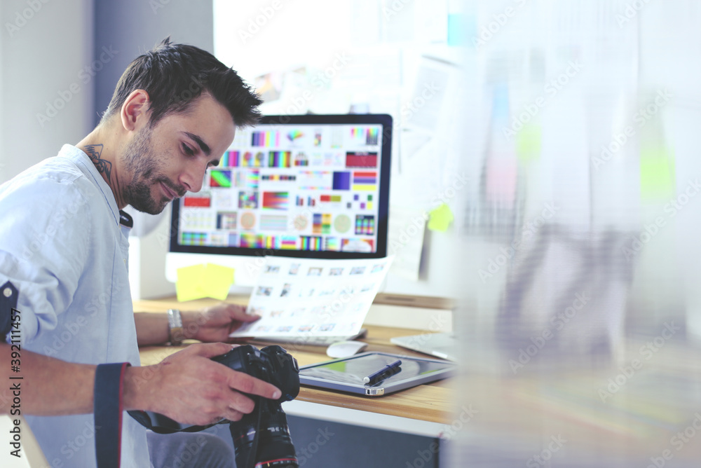 Poster portrait of young designer sitting at graphic studio in front of laptop and computer while working o