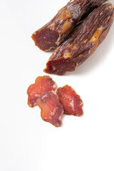 Dried sausage sliced into slices on a white plate. Elite meat product