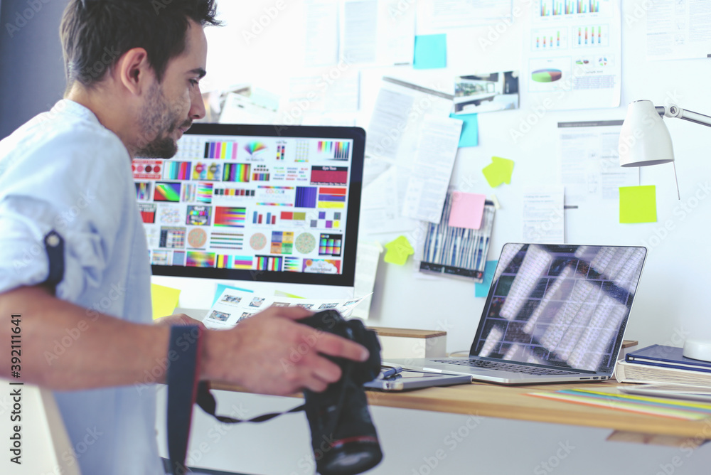 Poster portrait of young designer sitting at graphic studio in front of laptop and computer while working o