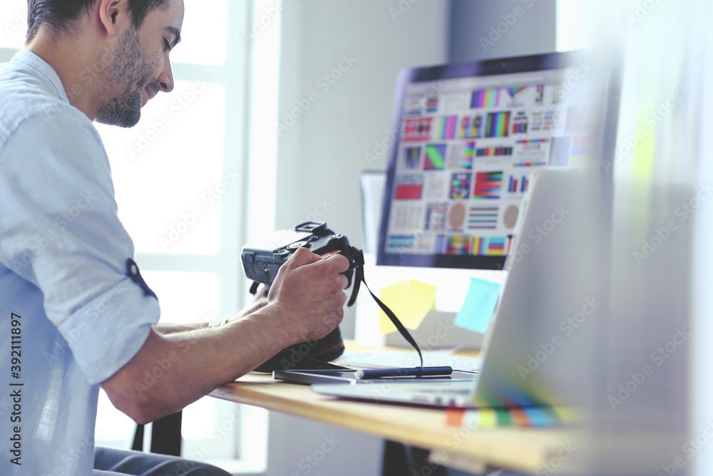 Poster portrait of young designer sitting at graphic studio in front of laptop and computer while working o