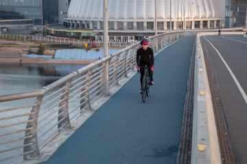 Woman training on a bicycle in the city at dawn. Yacht bridge St. Petersburg