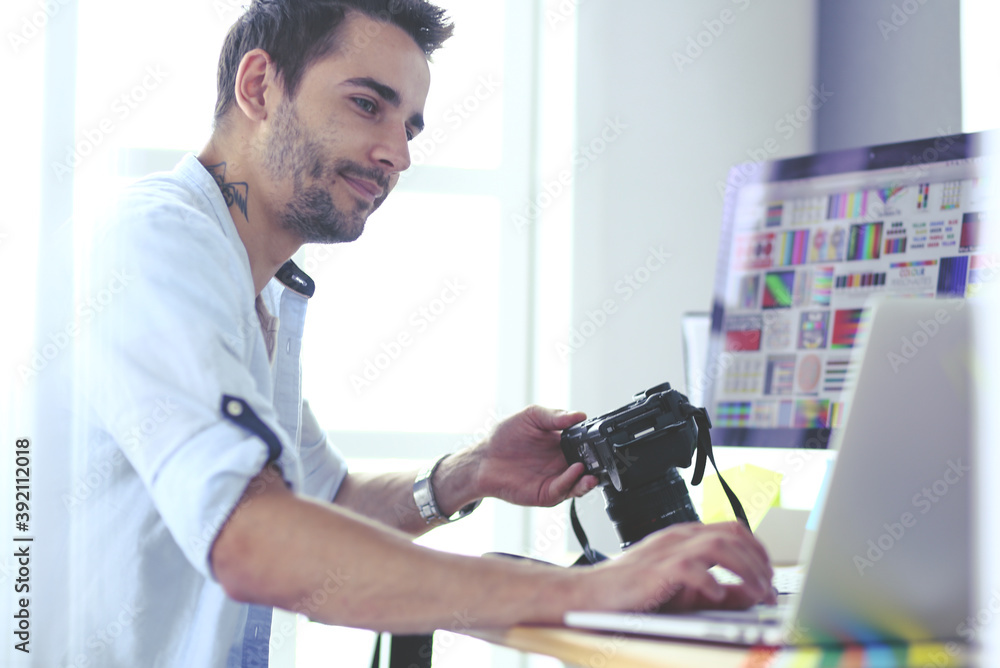 Poster portrait of young designer sitting at graphic studio in front of laptop and computer while working o