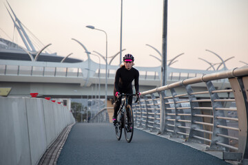 Fototapeta na wymiar Woman training on a bicycle in the city at dawn. Yacht bridge St. Petersburg