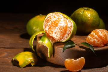 Food still life with green tangerines on round wooden podium and green leves.Close up of citrus fruits.