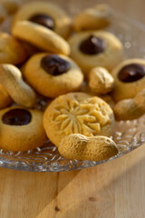 Light brown beige baked peanut cookies filled with dark chocolate, one by one on the plate, tasty Christmas sweets ready to eat