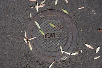 Close-up view of an iron cover plate for a sewer valve on the pavement of a city street seen directly from above