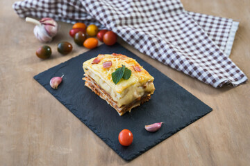 Portion of lasagna on wooden surface.