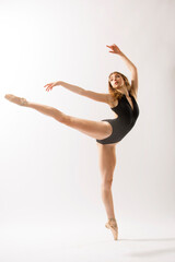 Ballerina in black leotard, dancing against a white background.