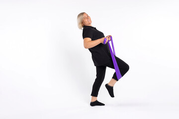 Senior woman doing a fitness workout at home using an elastic band. Photo on a white background. Healthy lifestyle and pandemic concept.
