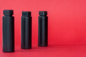 Black bottles with cream on a red background. Skin care, Moisturizing and nourishing or sunscreen.