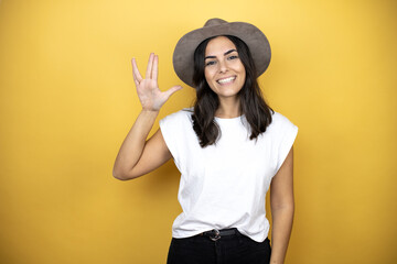 Beautiful woman wearing casual white t-shirt and a hat standing over yellow background doing star trek freak symbol