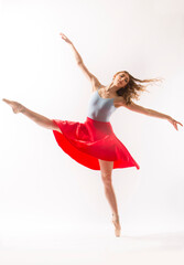 Ballerina in light blue leotard and red skirt, white background.